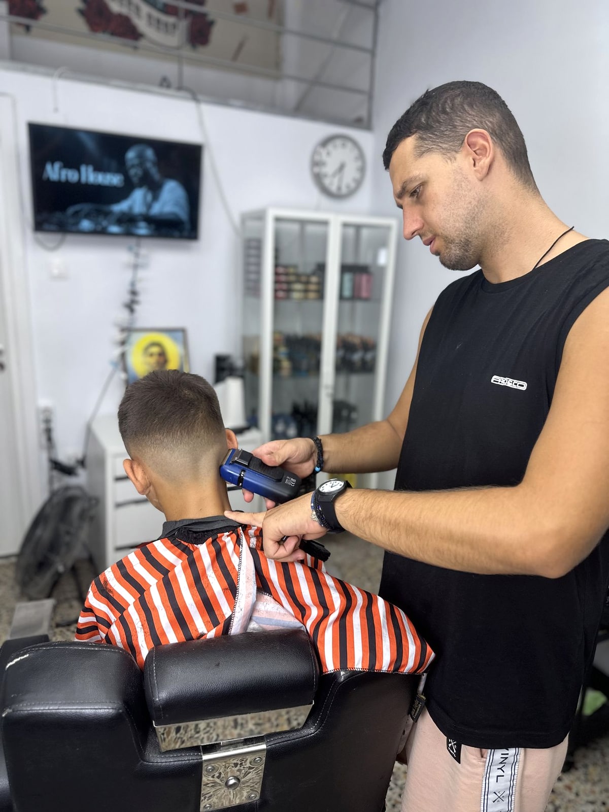 Ο Γιάννης κουρεύει ένα παιδί στο Massa Barber Shop
